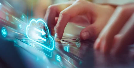 person tippt auf einem keyboard auf dem eine cloud abgebildet ist